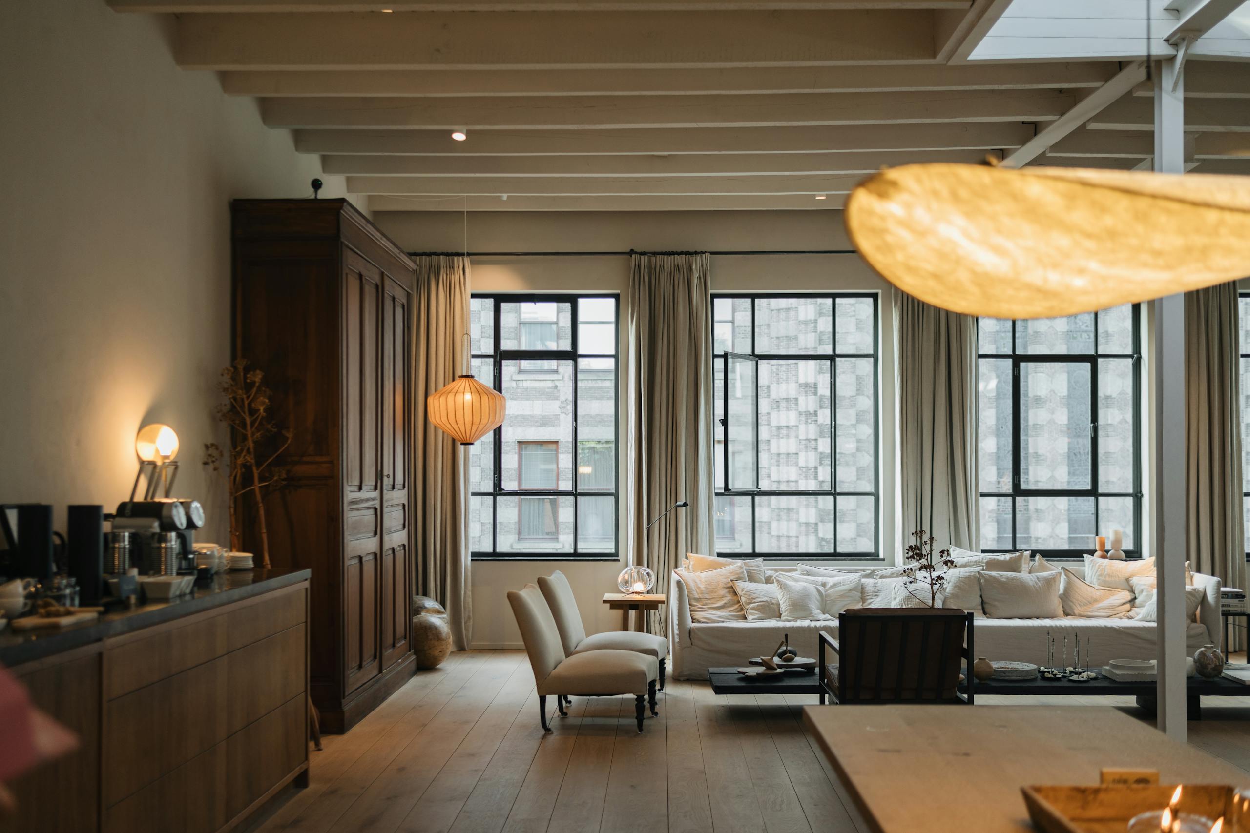 Sala de estar aconchegante com cortinas de tecido em tons neutros, sofá claro com almofadas decorativas e mesa de centro em madeira