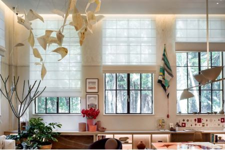 Quarto moderno com persianas automatizadas rolo bege fechadas, cama de casal em tons neutros e parede revestida em madeira.