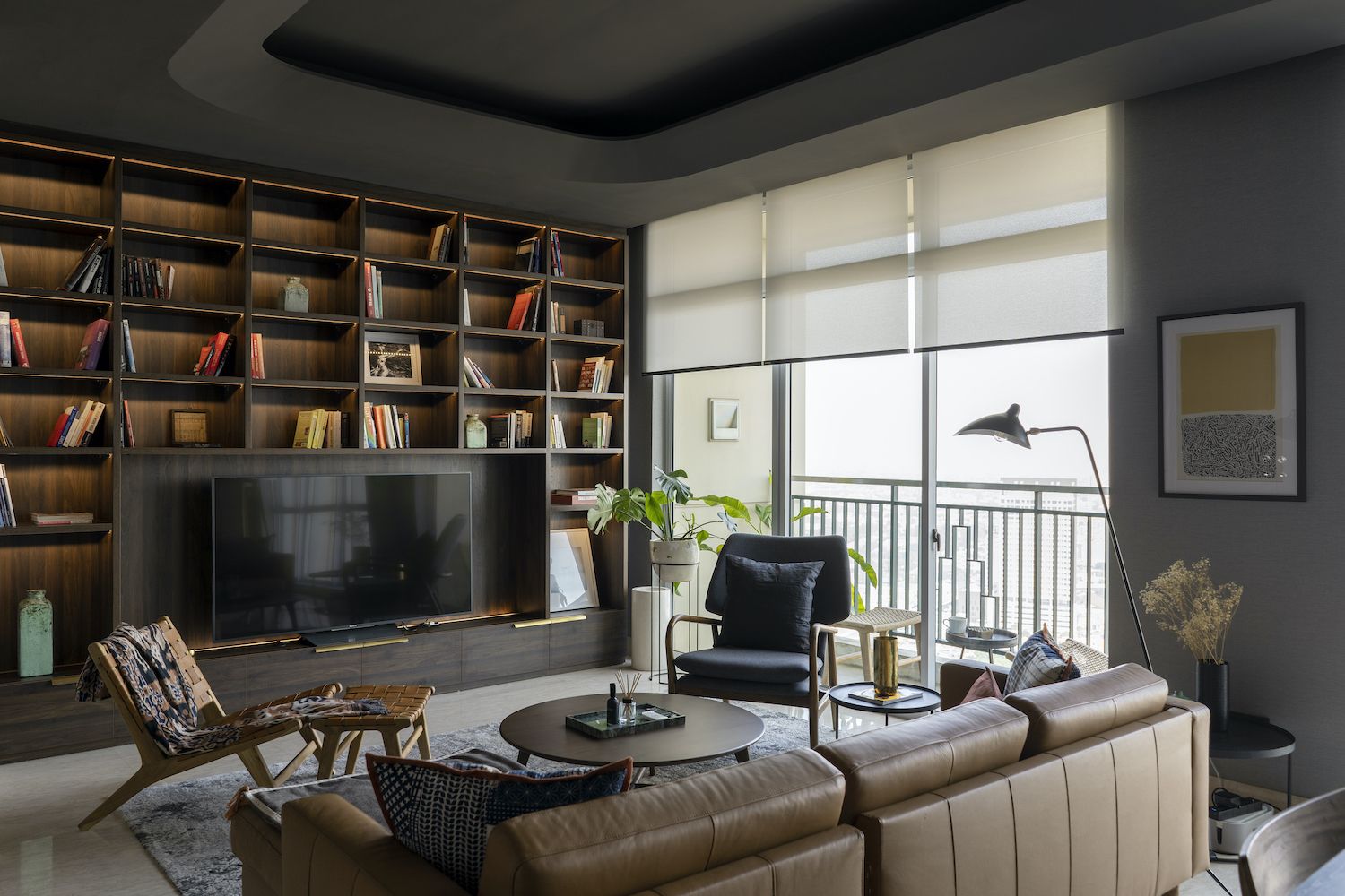 Persiana rolo em tecido claro instalada em sala de estar moderna, com controle de luminosidade natural junto à varanda, integrando sofás, estante planejada e decoração contemporânea.